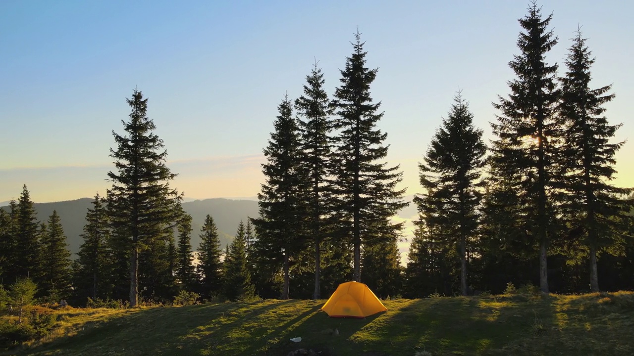 在阳光明媚的傍晚，鸟瞰山地露营营地的旅游帐篷。积极的旅游和徒步旅行理念视频素材