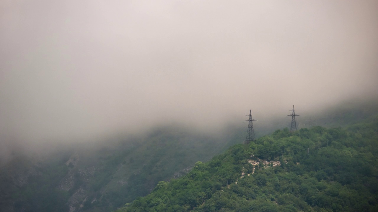 云从山上流下，穿过森林和电力线的极点。延时视频下载