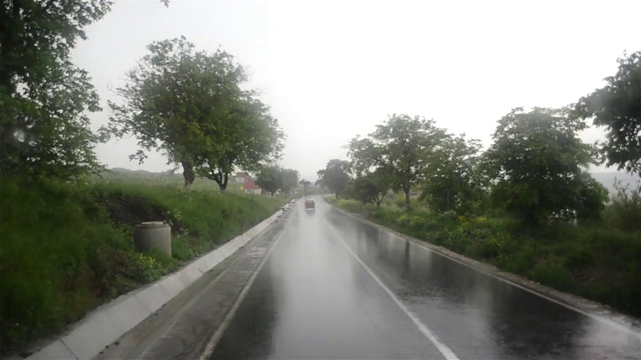 透过挡风玻璃看到的图像，一辆汽车行驶在铺满雨水的道路上视频素材