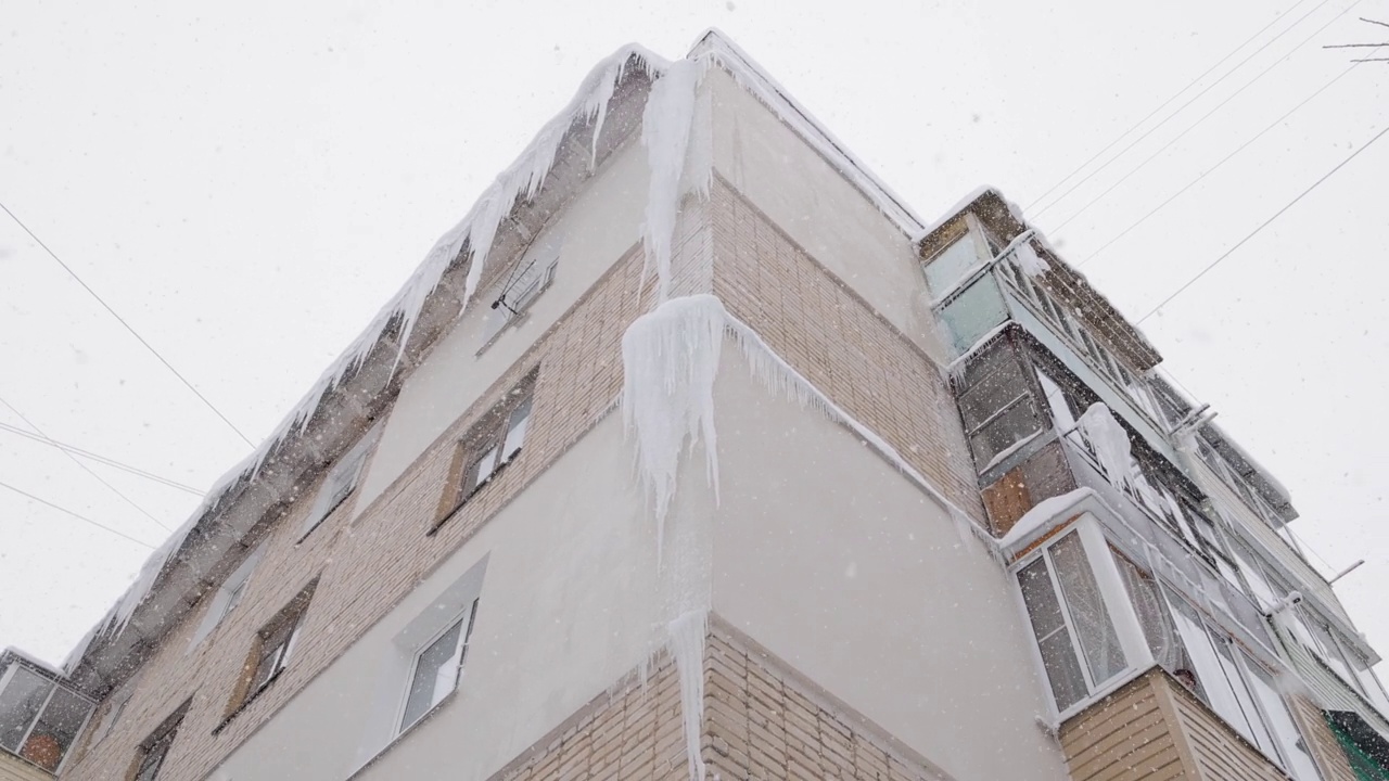 在冬天下雪的时候，俄罗斯赫鲁舍夫卡5层建筑的角落里有巨大的冰柱视频素材