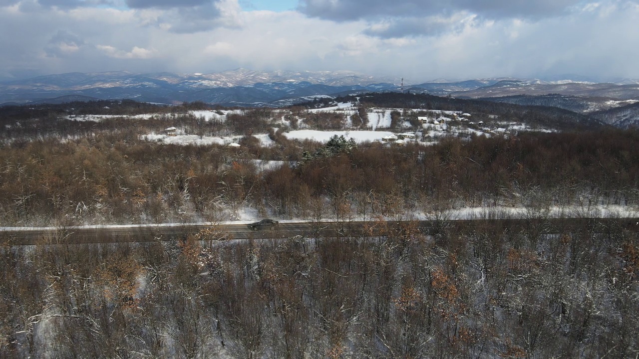 冬季，在塞尔维亚Knjazevac附近，在白雪皑皑的山脉中行驶的公路上的汽车的高角度空中侧视无人机视频视频素材