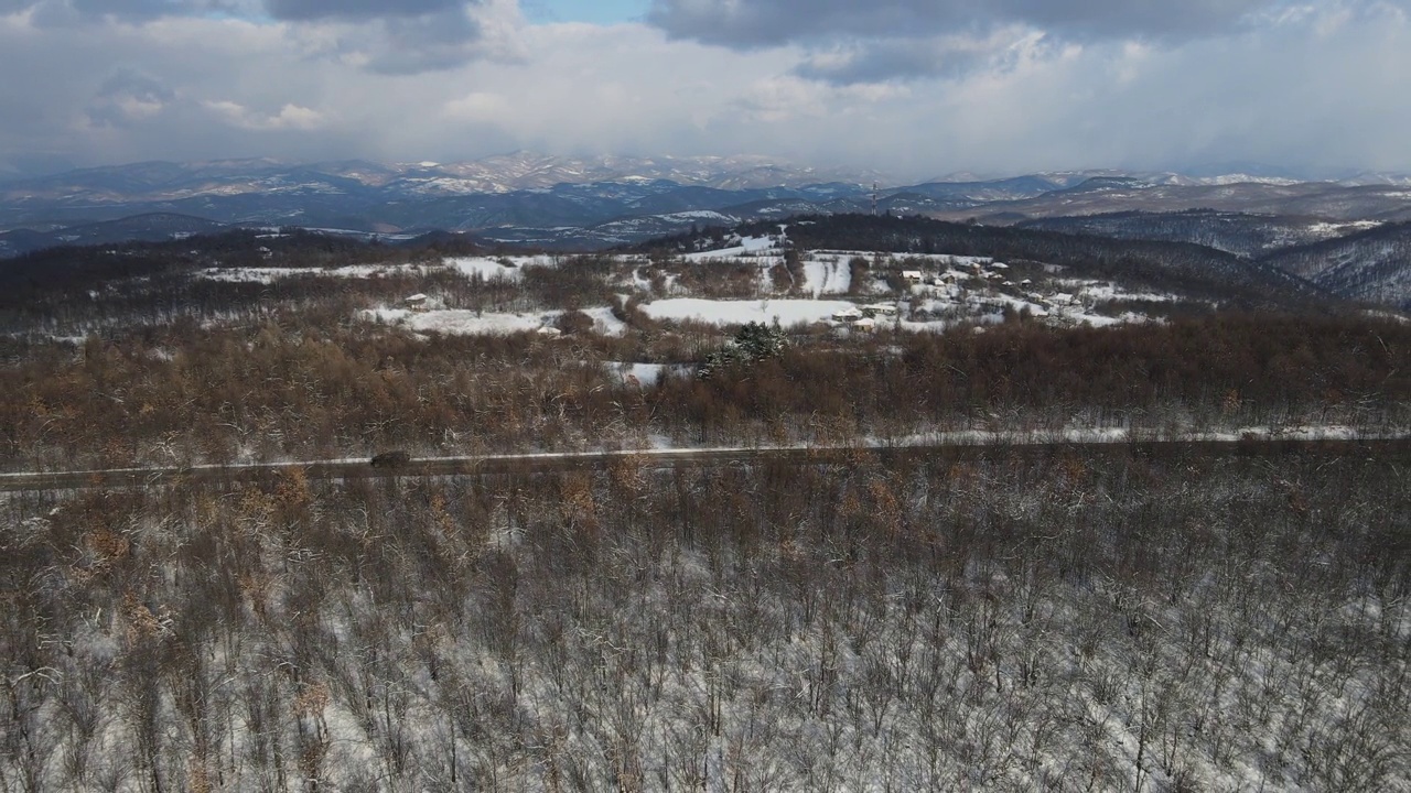 冬季，在塞尔维亚Knjazevac附近，在白雪皑皑的山脉中行驶的公路上的汽车的高角度空中侧视无人机视频视频素材