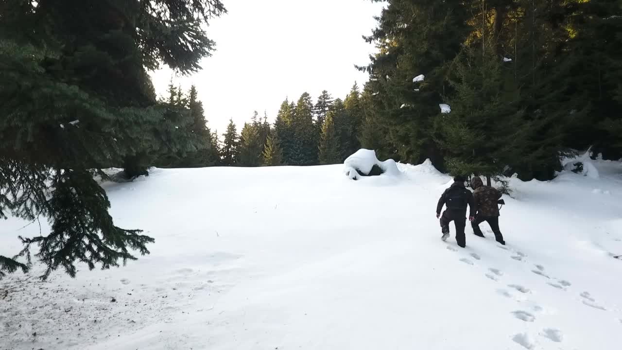 两个猎人拿着步枪走在白雪皑皑的森林里视频素材