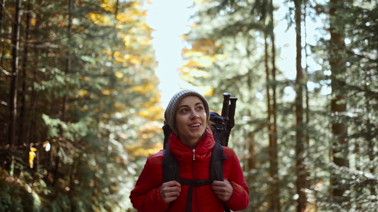 受快乐启发的女子背着背包走在林间小路上。秋季假期和假期旅行，女学生徒步旅行数字排毒，徒步旅行假期，接近自然，有氧训练视频素材