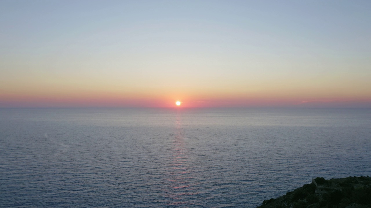 夕阳西下，天空泛着橘黄色，海浪平静的海面上的空中飞行。视频素材