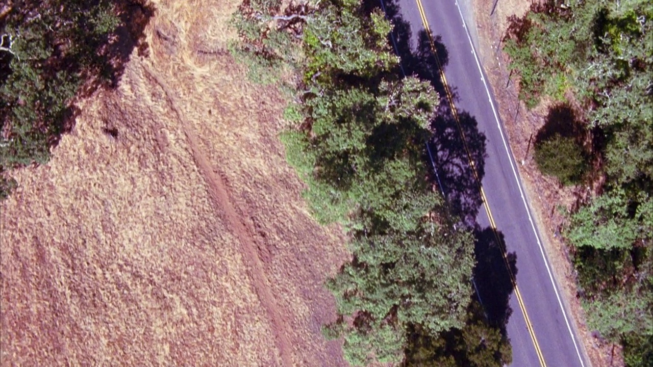 空中跟踪鸟瞰汽车行驶在弯曲的道路上通过干燥的山区。视频素材