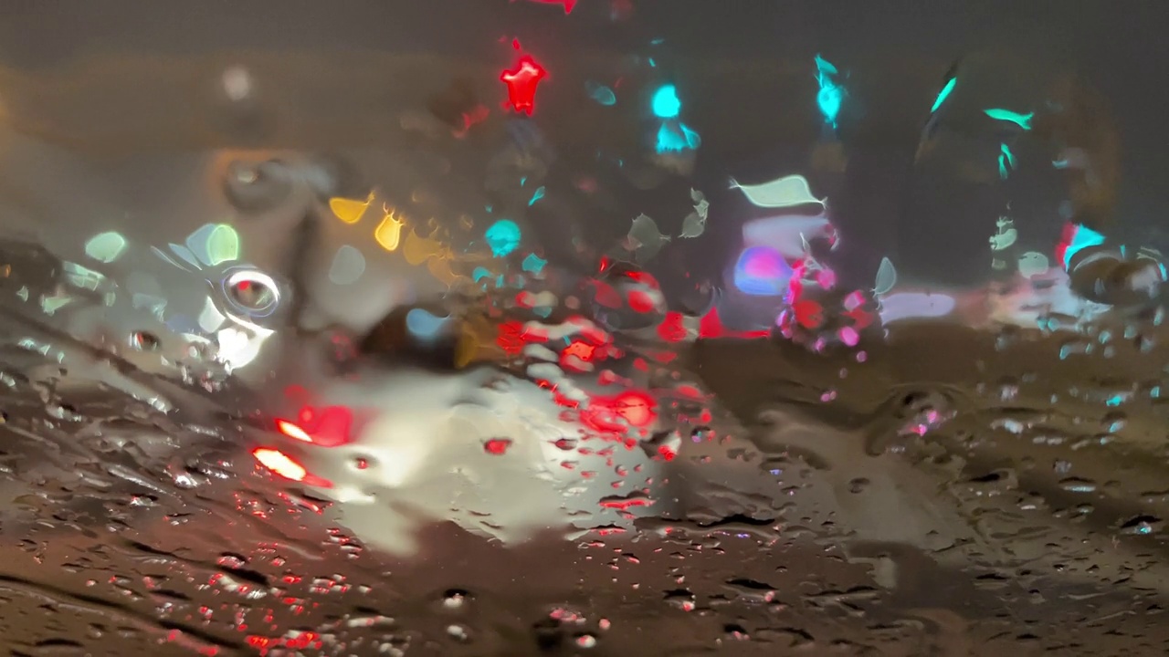 潮湿的道路上，汽车行驶在夜晚的冬季街道上。雨雪落在汽车的挡风玻璃上。在恶劣天气，车辆行驶在潮湿、多雨、湿滑的道路上视频素材