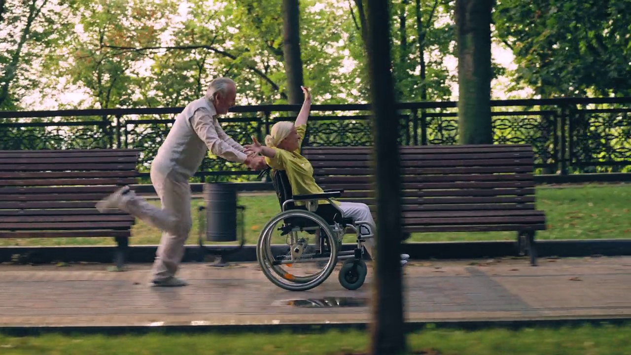 兴奋的老男人推着轮椅奔跑，快乐的女人在一起视频下载