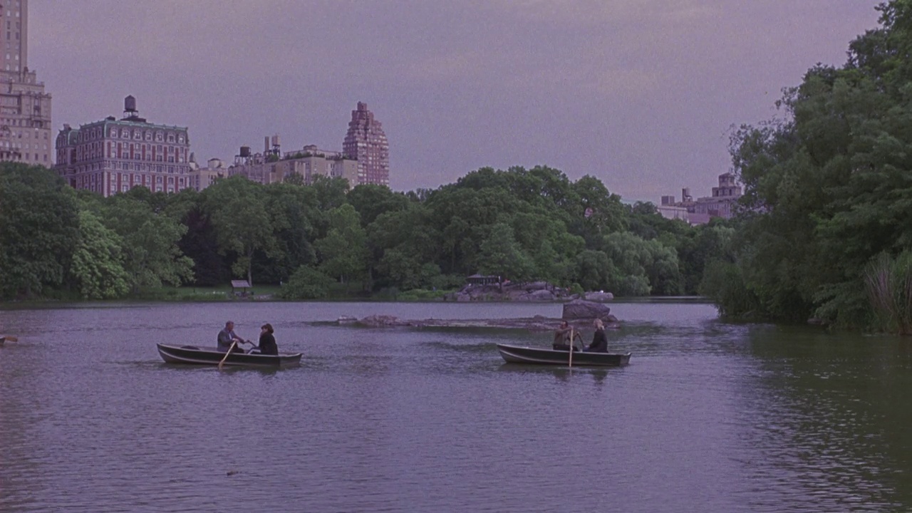 广角湖或水库情侣，人们划着划艇。Pan to walk around water, couples walk, taking a nice stroll。纽约中央公园。视频素材