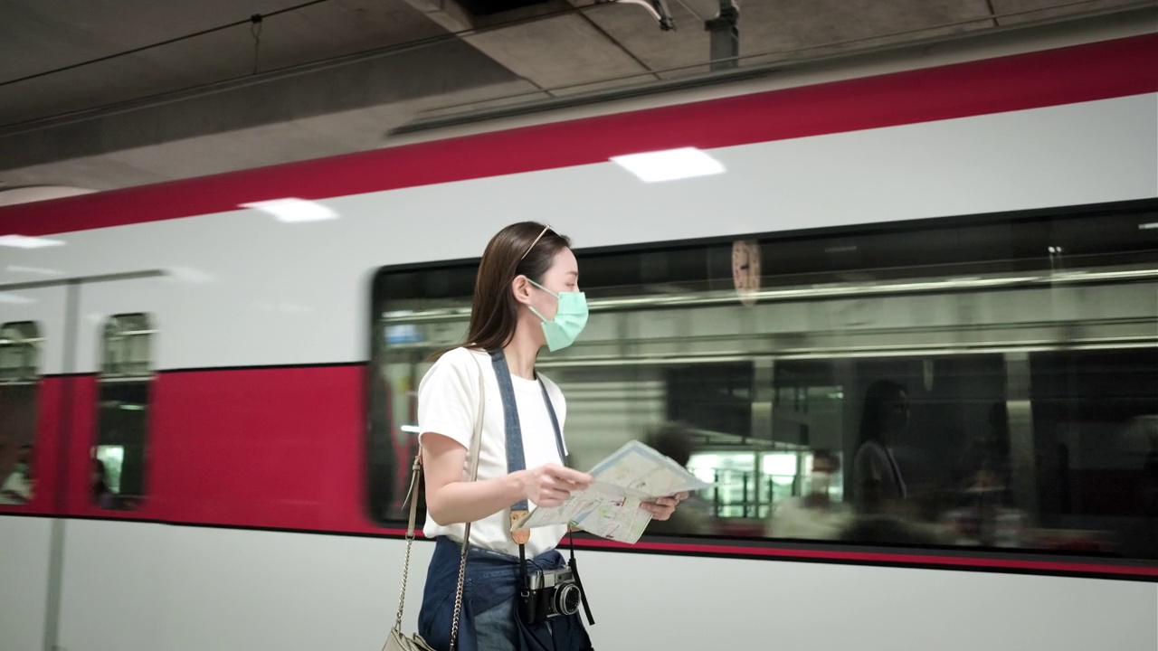 带着口罩的亚洲女性游客在火车站搜索地图。视频素材