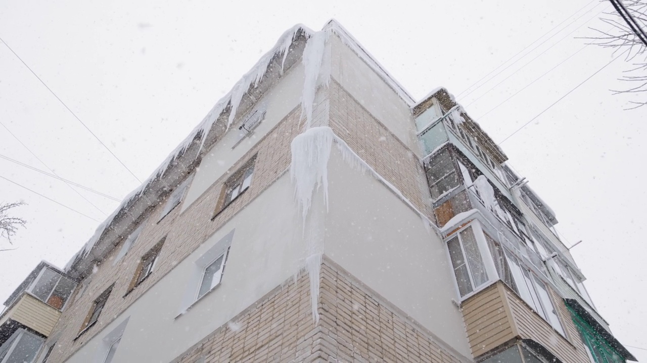 在冬天下雪的时候，俄罗斯赫鲁舍夫卡5层建筑的角落里有巨大的冰柱视频素材