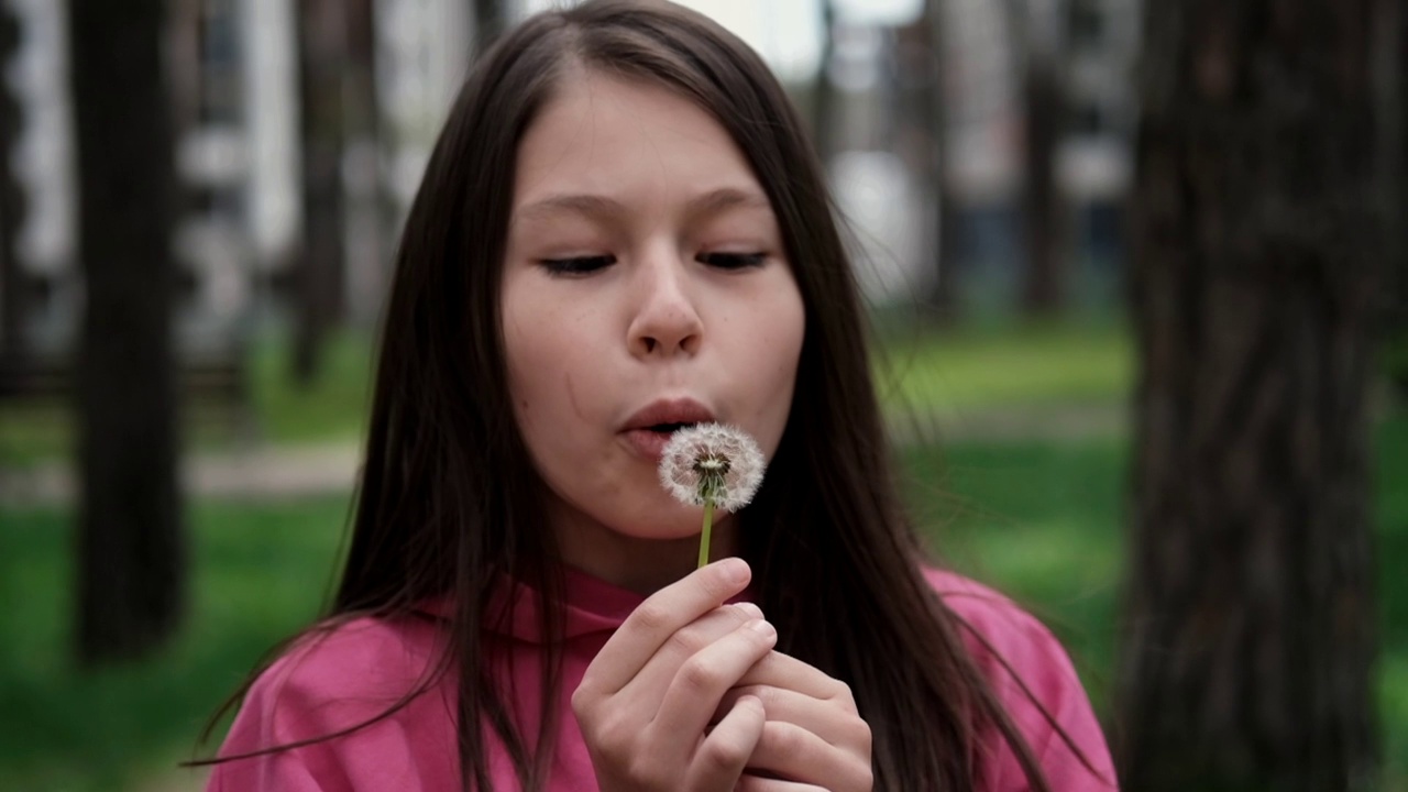 可爱的小女孩在公园里吹蒲公英。快乐的孩子在户外玩得很开心。假期或节日。额外的慢动作视频素材