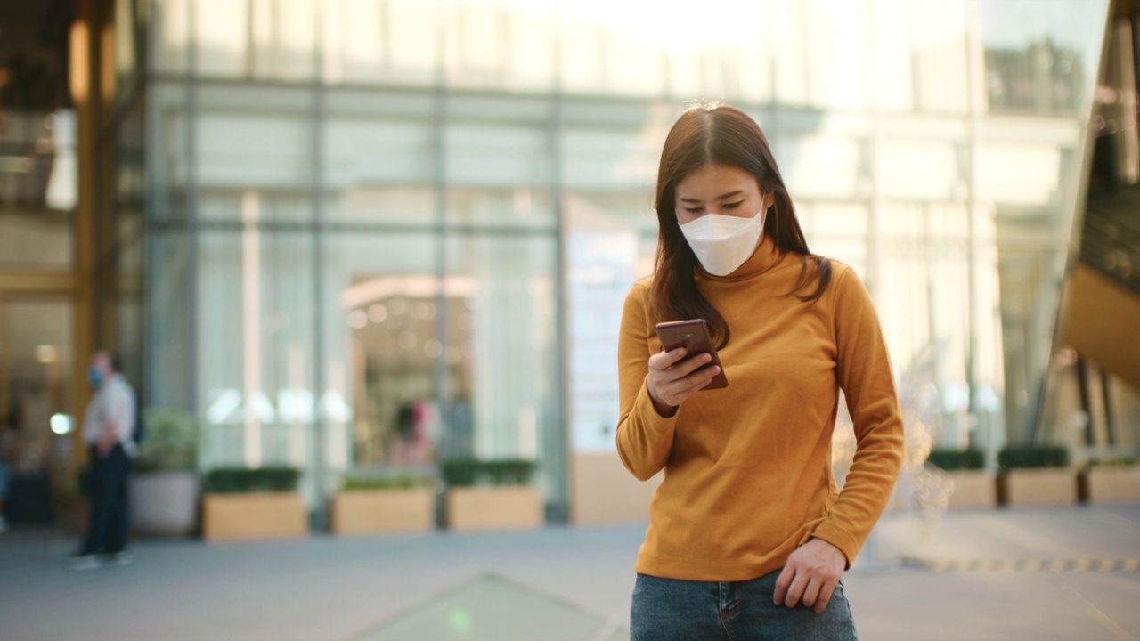 女子用智能手机防病毒口罩视频素材