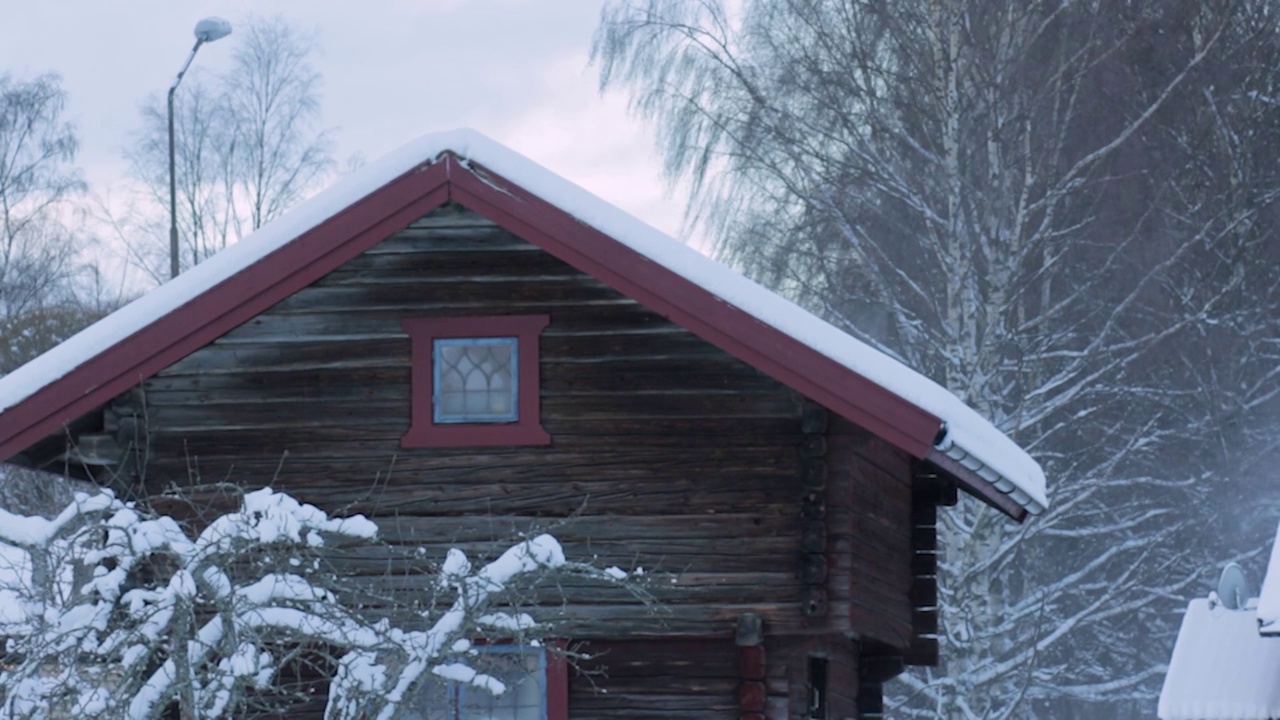 雪从小屋的屋顶上吹在风中视频素材