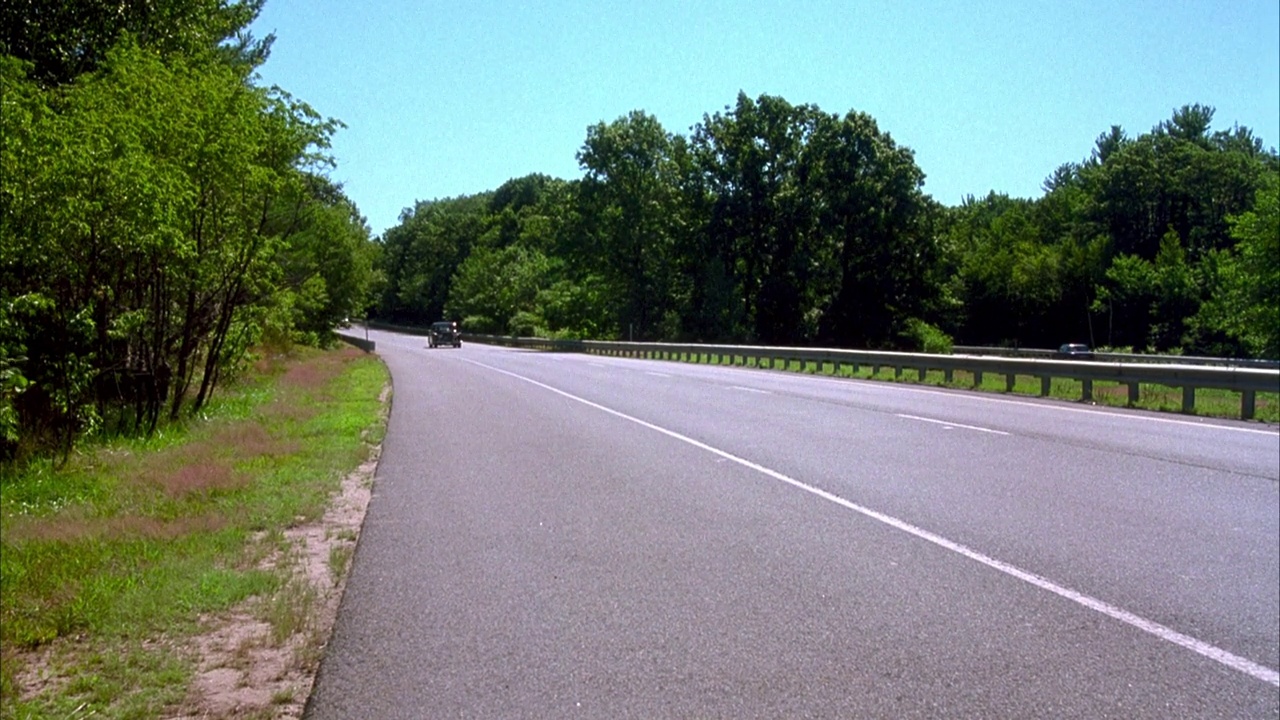 中等角度的i-93或i-95高速公路通过马萨诸塞州的乡村。看到汽车和面包车向镜头移动。镜头短暂地跟踪了勃艮第或红色汽车(1963年劳斯莱斯银云iii)在高速公路上。在右边看到路标“波士顿75英里”。视频素材