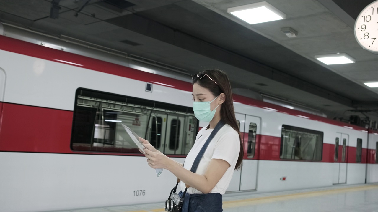 带着口罩的亚洲女性游客在火车站搜索地图。视频素材