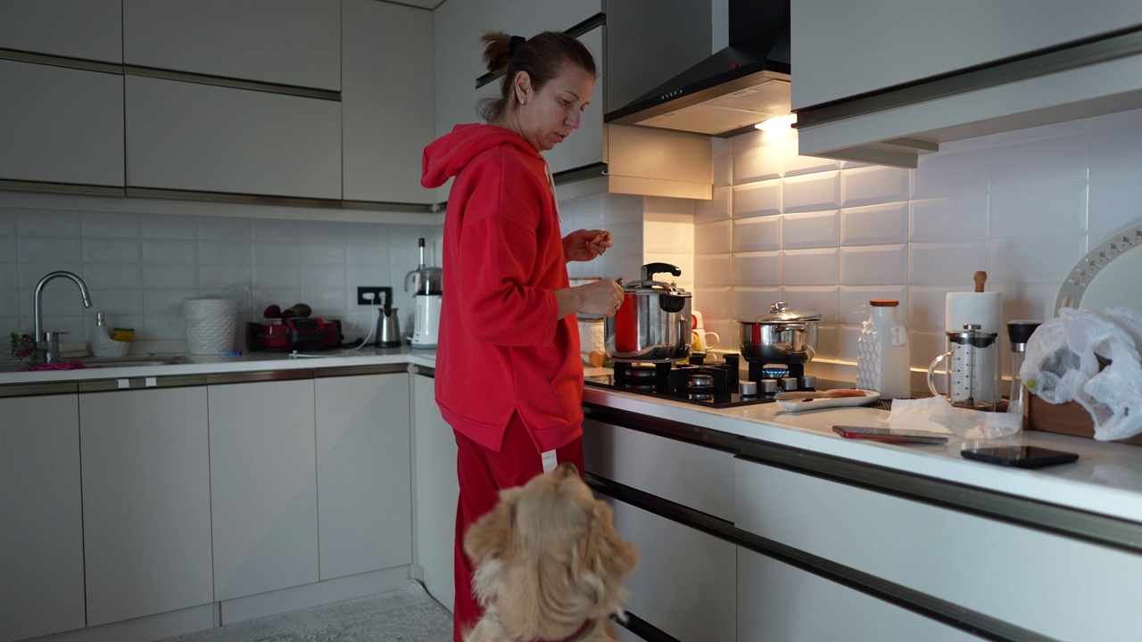 成熟的女人和她的金毛猎犬在厨房做饭。视频素材