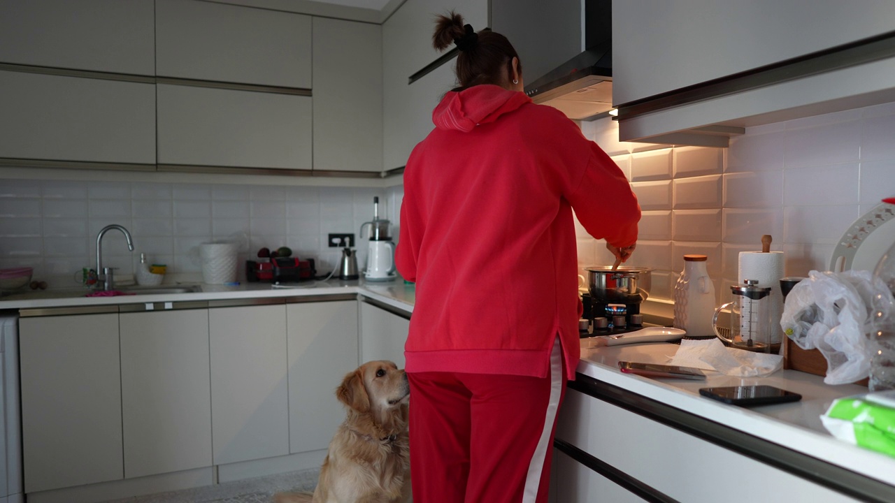 成熟的女人和她的金毛猎犬在厨房做饭。视频素材