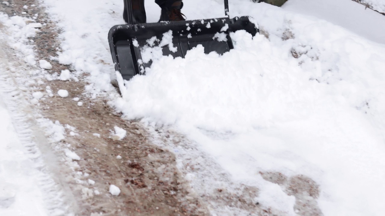 清除积雪的特写。一个男人拿着一个大铁笼铲在外面清理雪视频素材