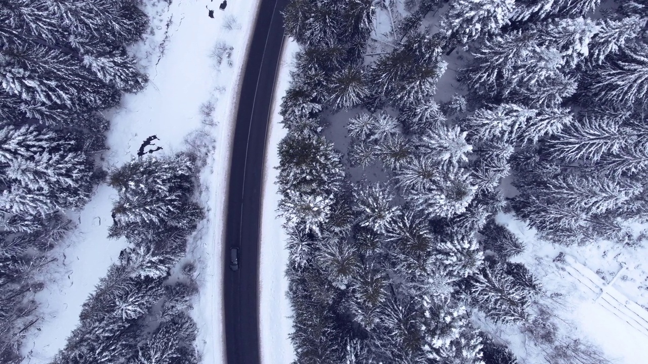 鸟瞰图雪山森林与汽车驾驶冬季道路。视频素材