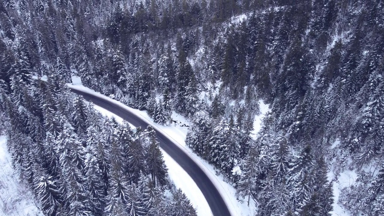 鸟瞰图雪山森林与汽车驾驶冬季道路。视频素材