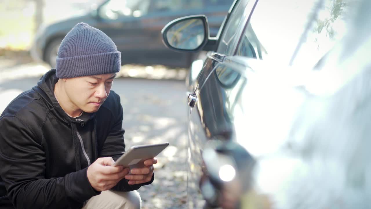 偷车贼正在偷车。黑进汽车系统。兜帽男试图用平板电脑破坏汽车的安全系统视频素材