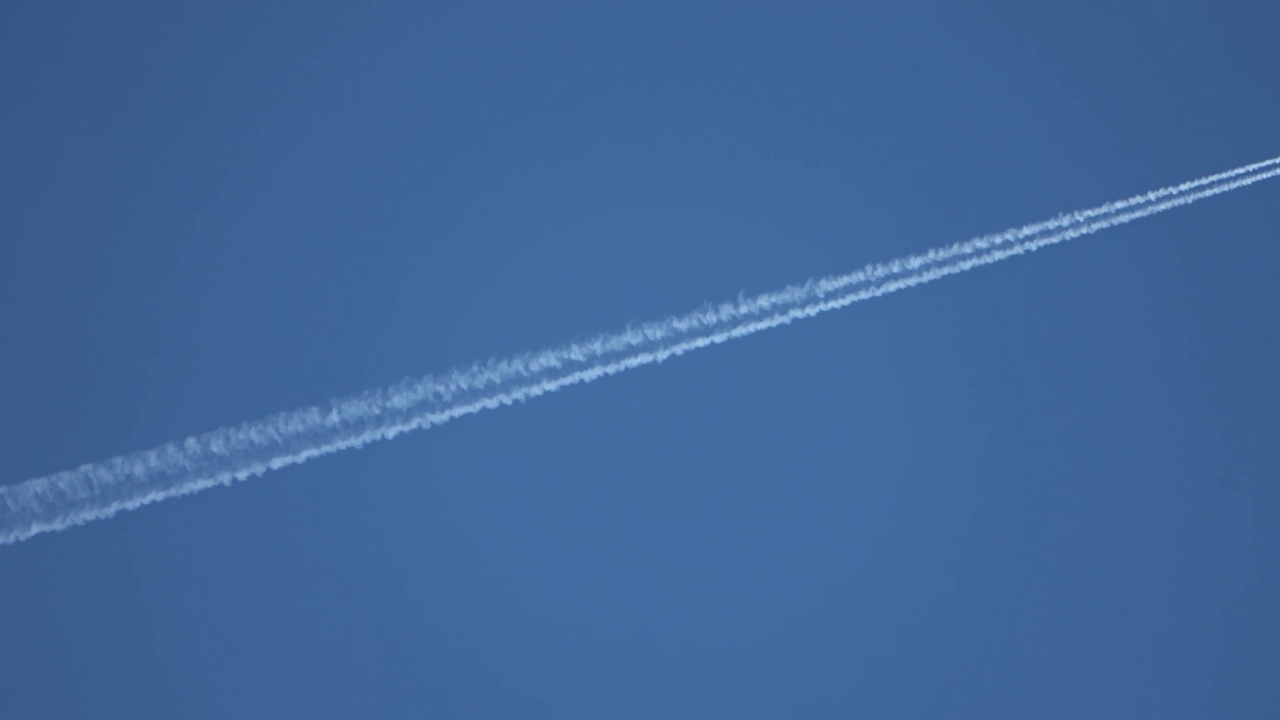 两架喷气式飞机在高空互相飞行，在清澈的蓝天上留下了尾迹。视频素材