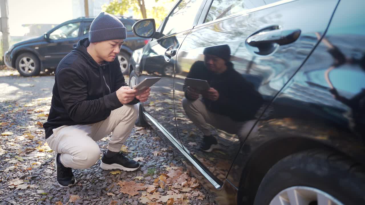 偷车贼正在偷车。黑进汽车系统。兜帽男试图用平板电脑破坏汽车的安全系统视频素材