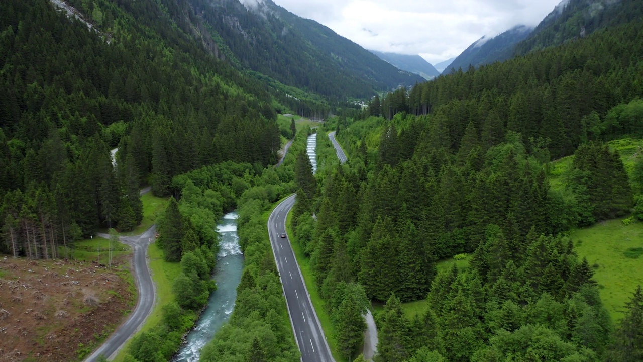 空中汽车跟随镜头沿着蓝色的河流在美丽的紫色森林的山路行驶。奥地利蒂罗尔州视频素材