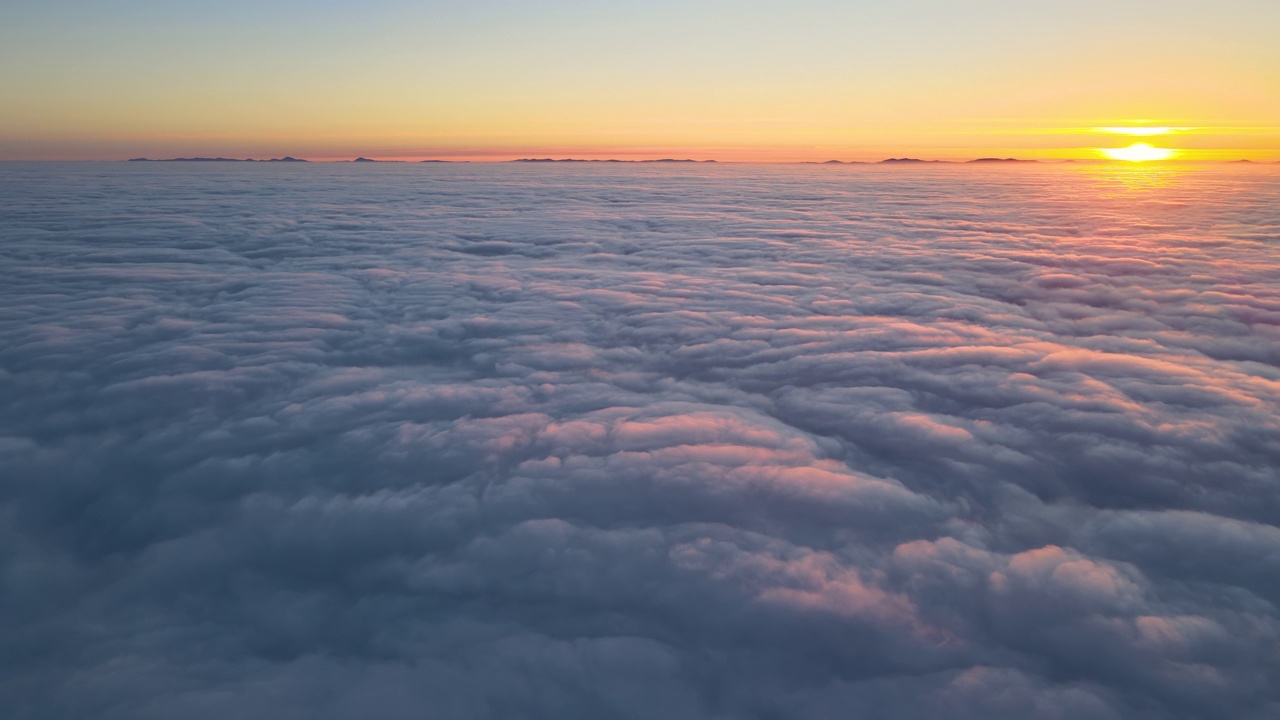 从高空俯瞰，浓密蓬松的积云在傍晚飞舞。从飞机窗口看到的令人惊叹的日落视频素材