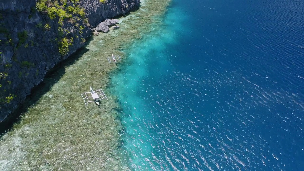 空中4k无人机拍摄到停泊在珊瑚礁边缘的游船。El Nido，菲律宾巴拉望岛视频素材