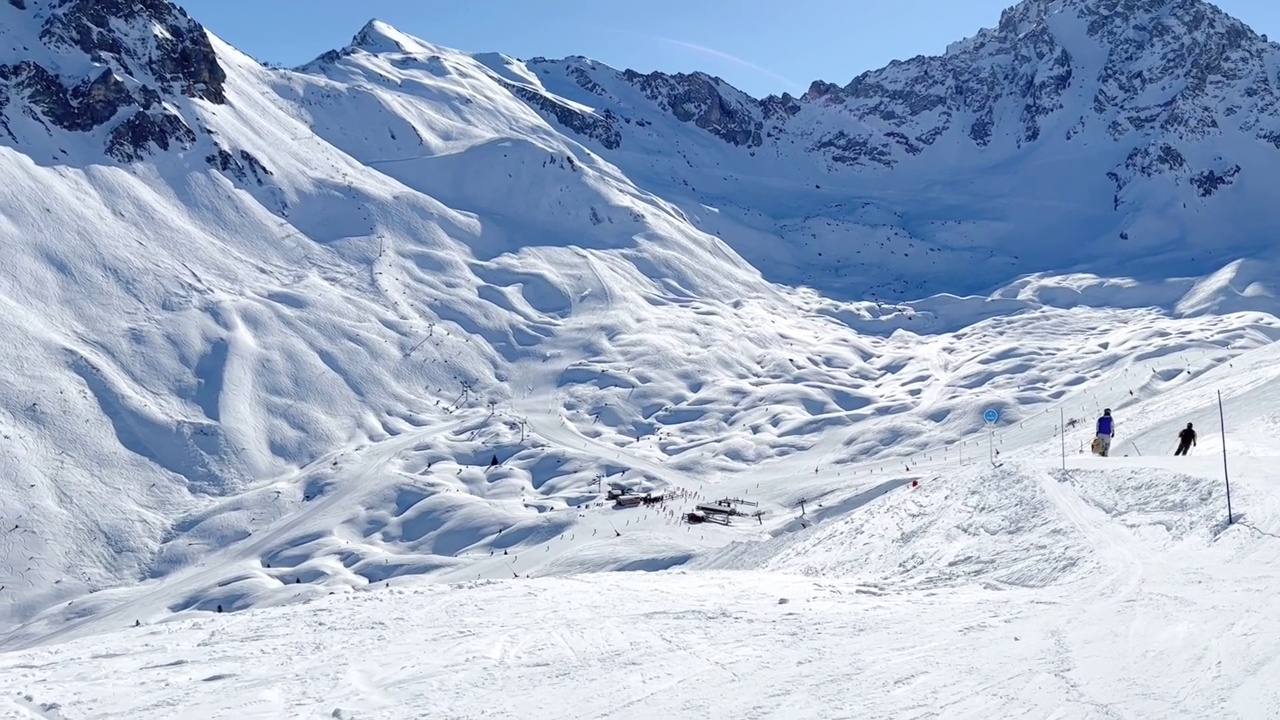 人们在著名的滑雪胜地Courchevel宽阔的斜坡上滑雪。视频素材