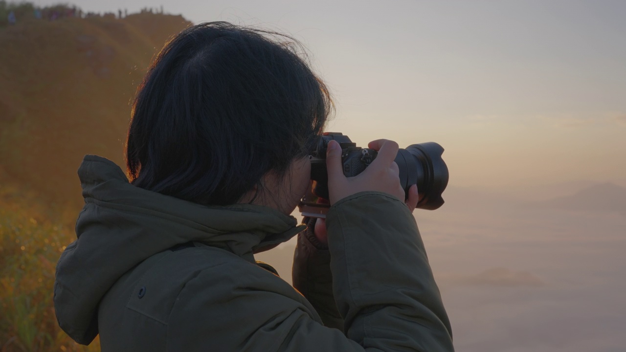 女背包客在摄影之旅中悠闲地捕捉雾山的形象。视频素材