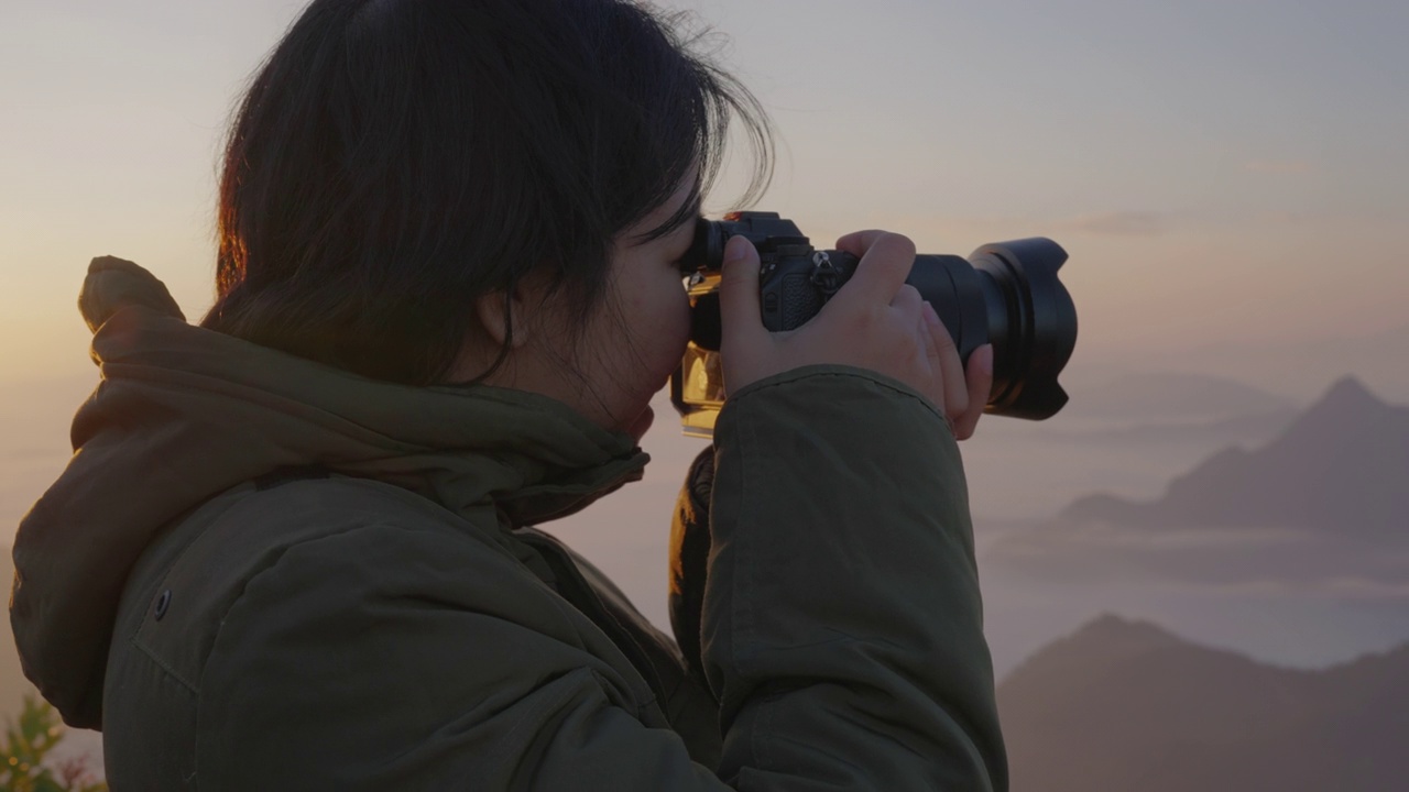 女背包客在摄影之旅中悠闲地捕捉雾山的形象。视频素材