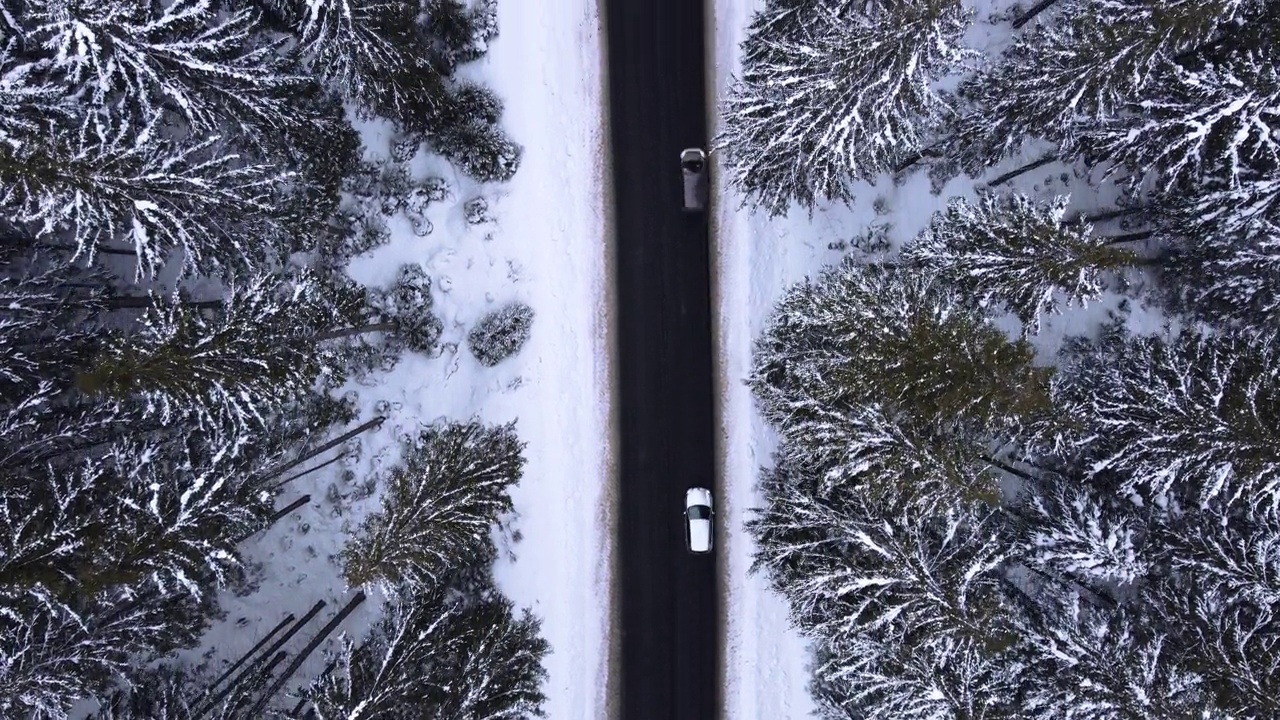 鸟瞰图雪山森林与汽车驾驶冬季道路。视频素材