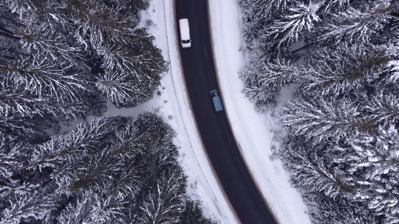 鸟瞰图雪山森林与汽车驾驶冬季道路。视频素材