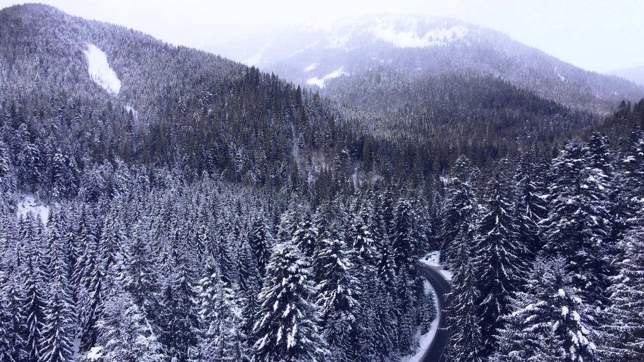 鸟瞰图雪山森林与汽车驾驶冬季道路。视频素材