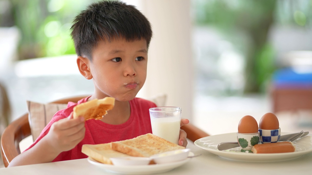 亚洲小孩早餐喝一杯牛奶。健康早餐的概念视频素材