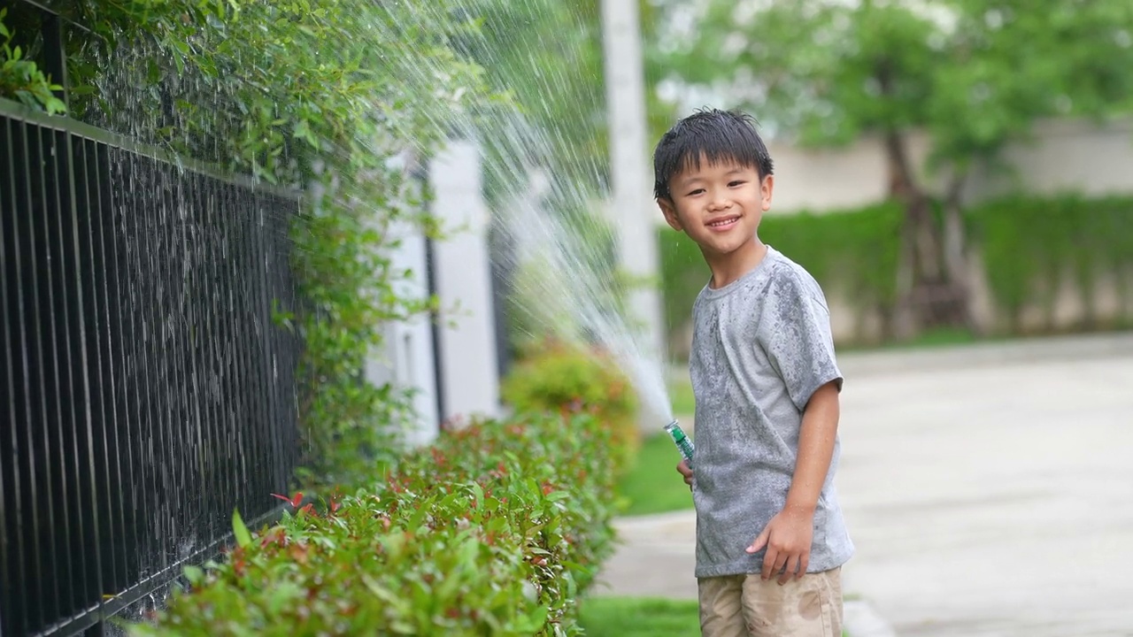 亚洲小孩穿着靴子在公园玩泼水和泥巴。夏天和快乐的概念视频素材