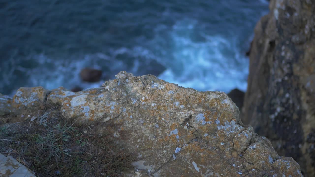 蓝蓝的海浪拍打在岩石山的悬崖上视频素材