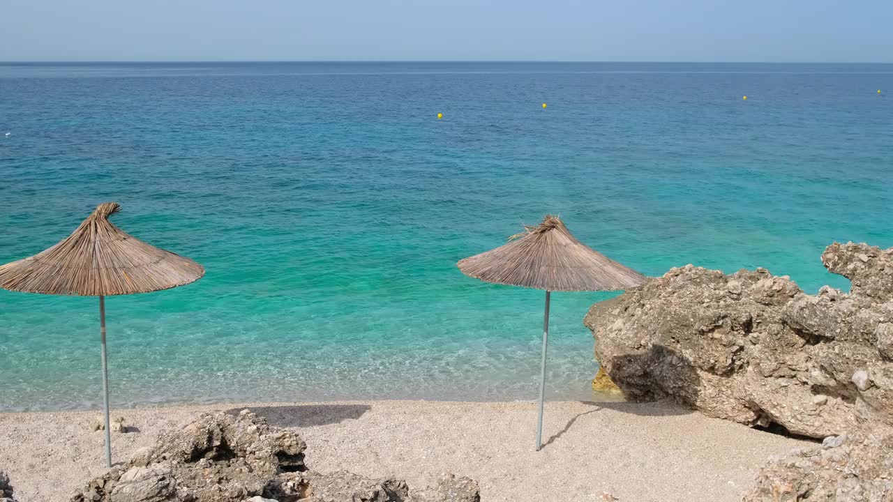 美丽的空旷的野生海滩上有遮阳伞和美丽平静的海水视频素材