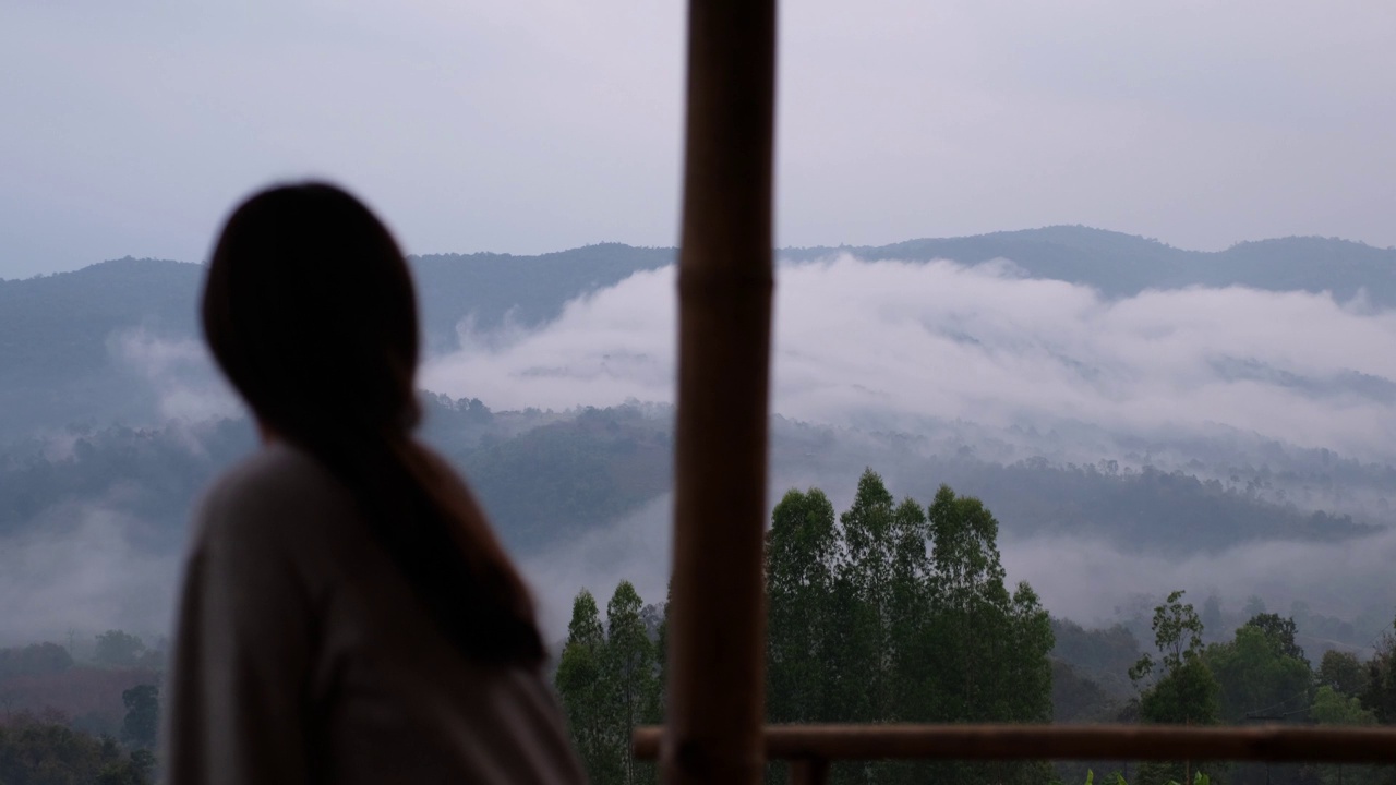 模糊的一个女人坐在看美丽的山景在雾天视频素材