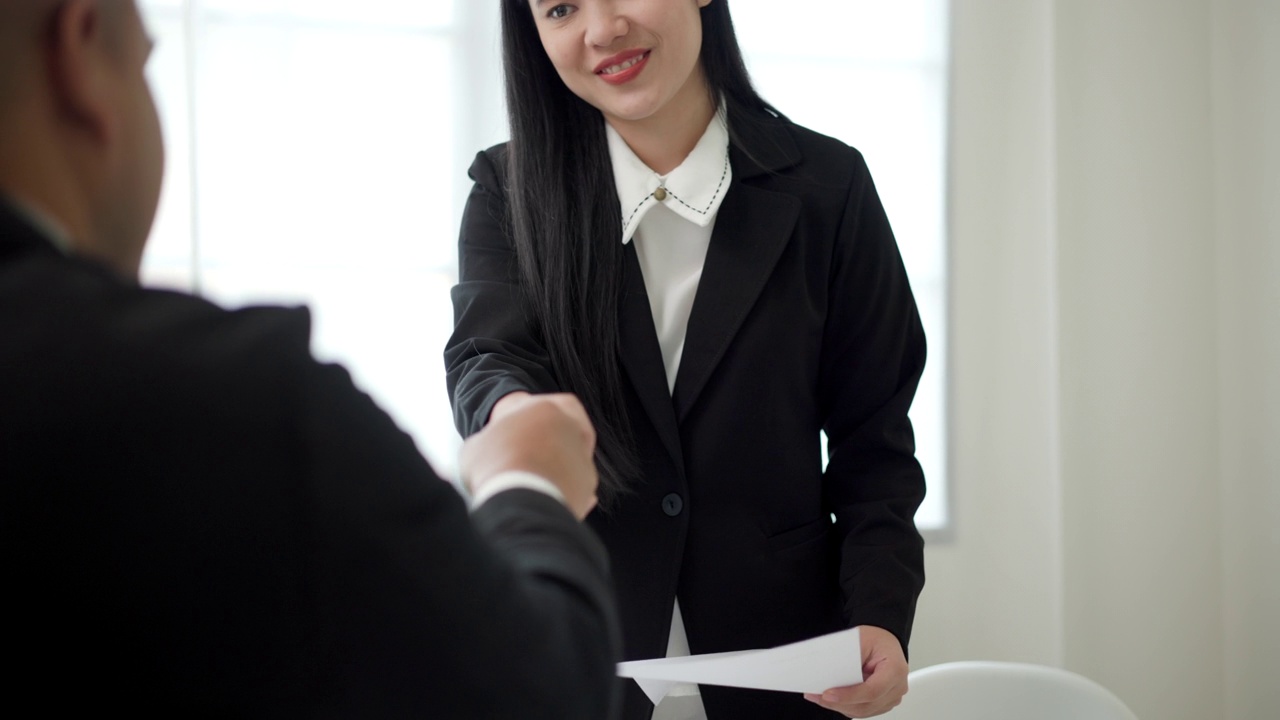 一名聪明的亚洲女性在求职面试前与人力资源部的工作人员握手。快乐的女人寻求者或保险经纪人提出一项业务。女商人发送简历。视频素材