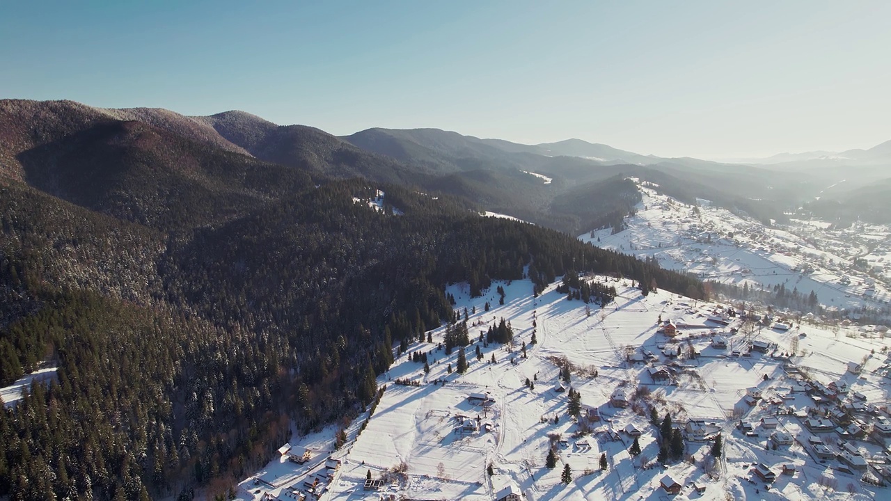 白雪覆盖的山脉和小山上的村庄。鸟瞰图。视频素材