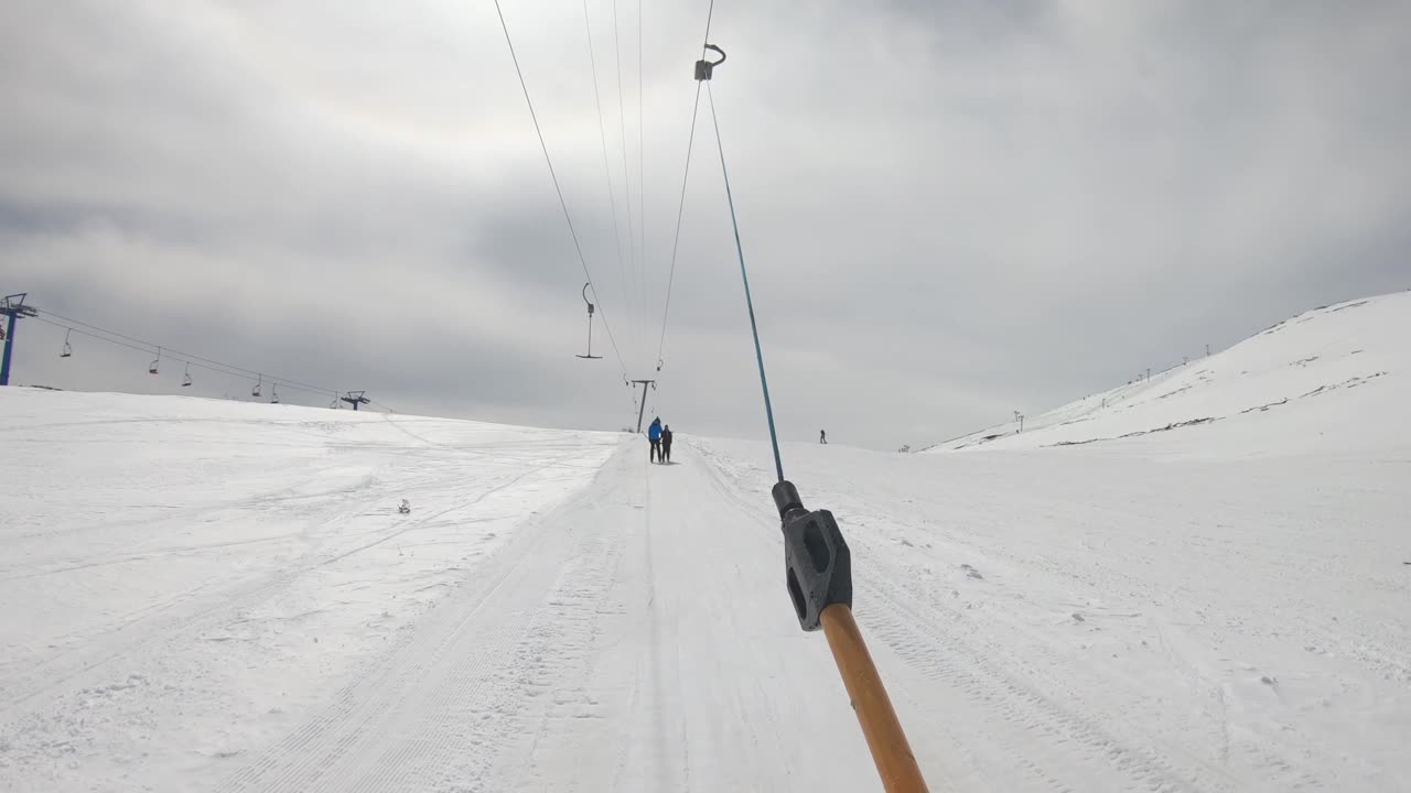 滑雪者手持索道t形杆，在滑雪场、坡道、坡道上升视频素材