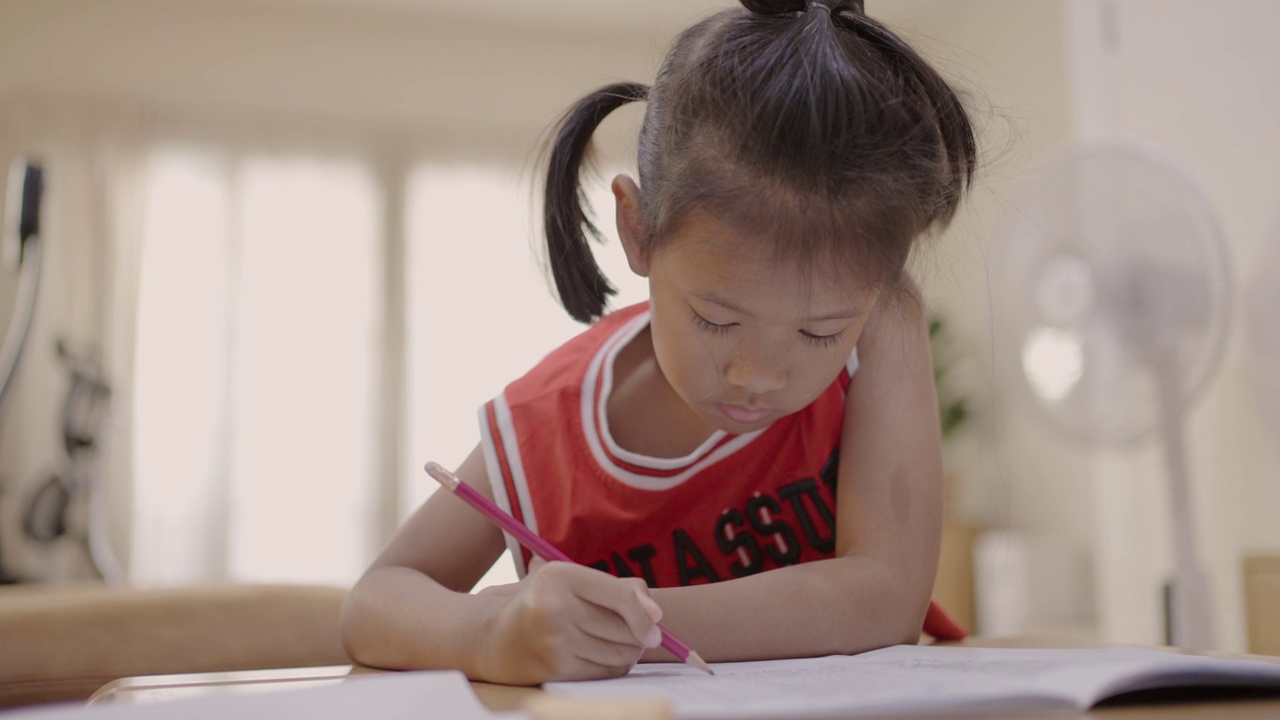 一个亚洲小女孩在家里学习写字视频素材