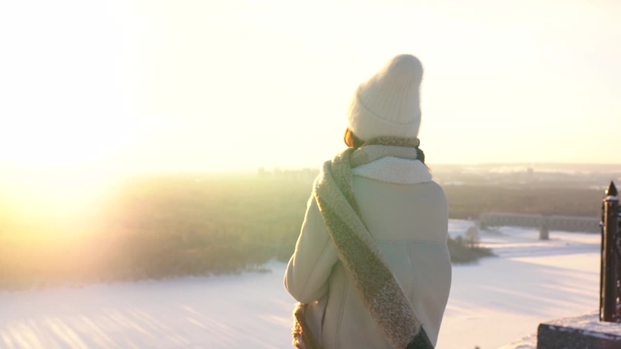 跟踪拍摄的快乐的年轻女子，在美丽的冬季雪景上欣赏观景台，喝着热咖啡。视频素材