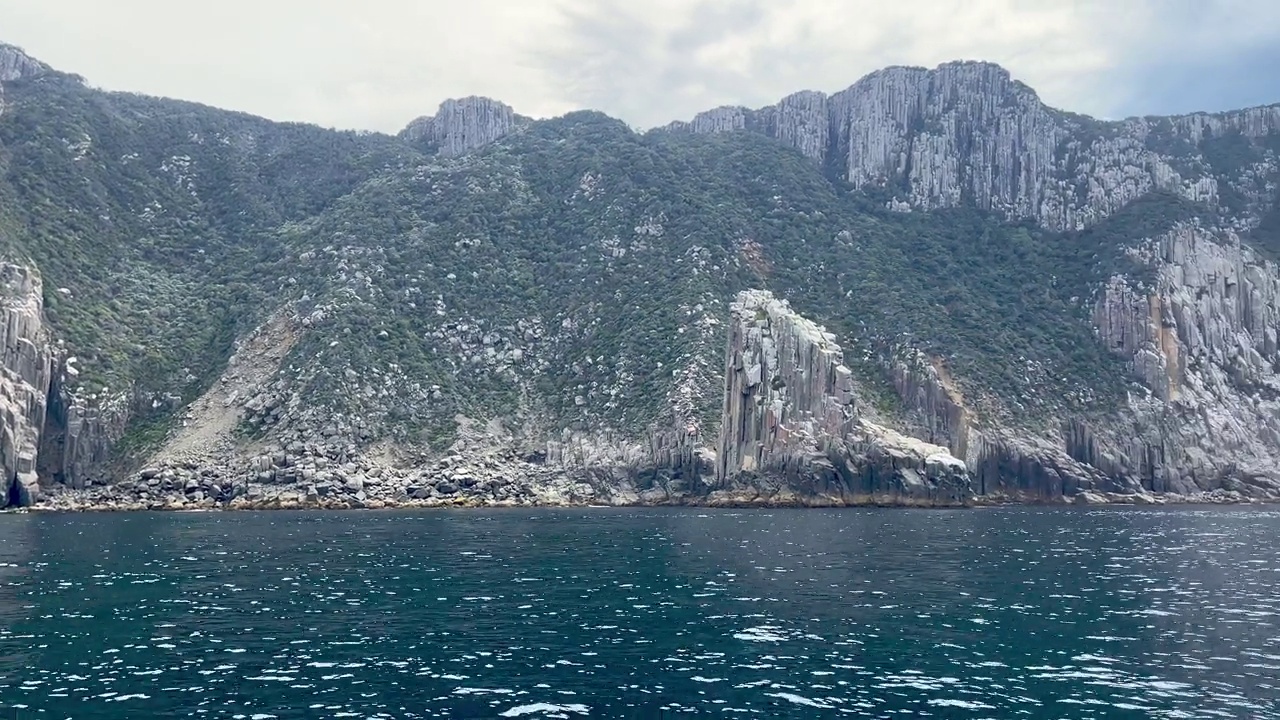 沿着多岩石的海岸线，高高的海崖，塔斯马尼亚岛的船景视频素材