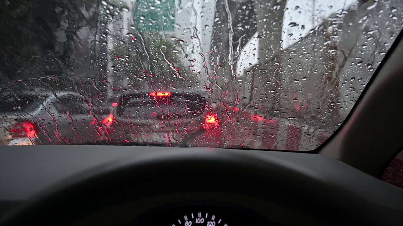 雨滴从车内的视野落在汽车挡风玻璃上。暴雨期间交通堵塞。视频下载