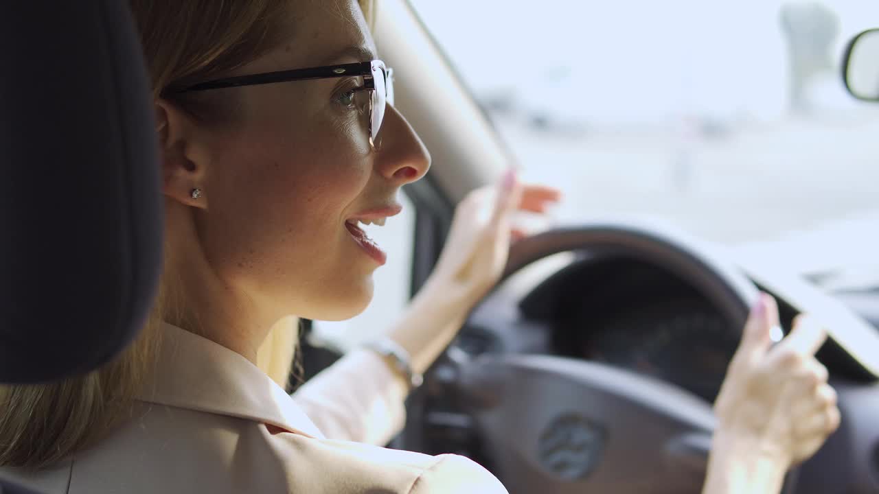 兴奋的金发女人跳舞驾驶汽车，享受汽车收音机里最喜欢的歌曲视频素材